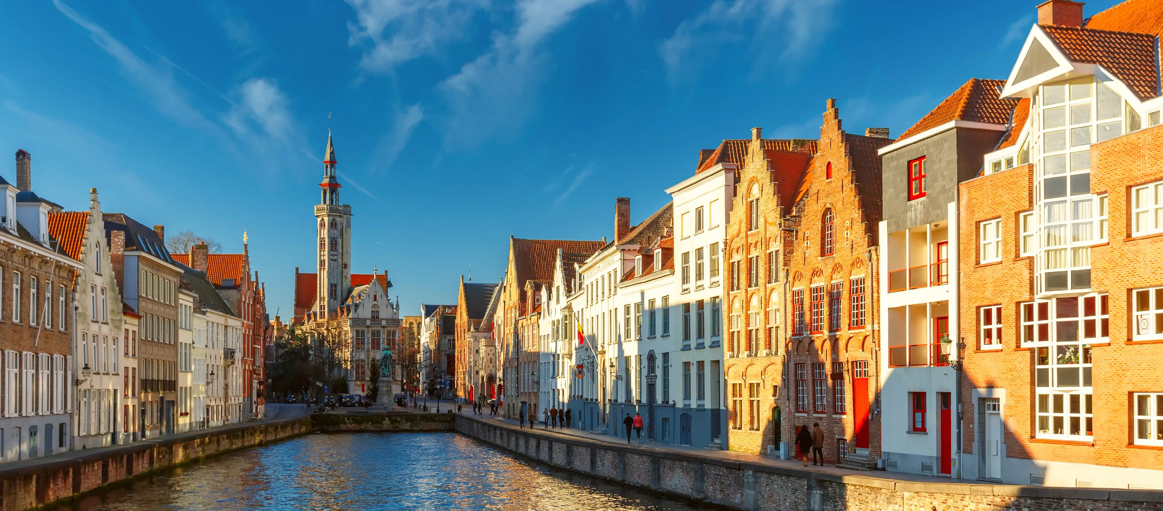 Uma vista panorâmica de um canal em Bruges, Bélgica, com casas históricas com escadas, para um guia sobre recrutamento e contratação na Bélgica.