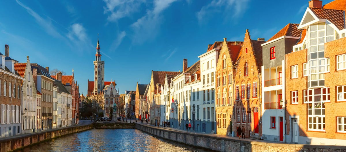 A scenic view of a canal in Bruges, Belgium, with historic step-gabled houses, for a guide on recruiting and hiring in Belgium.