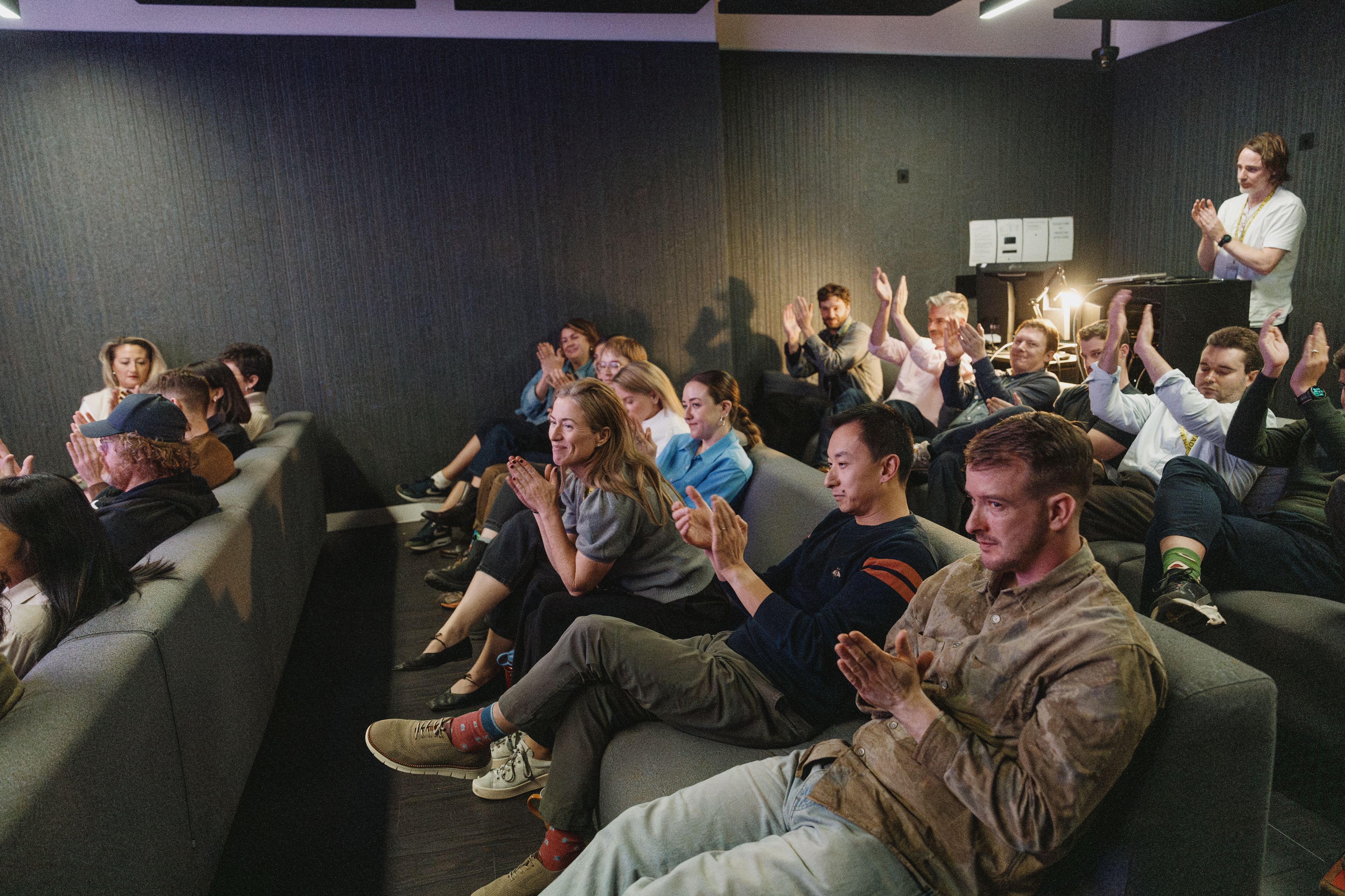 The whole team in the studio’s cinema room, applauding at the company meeting
