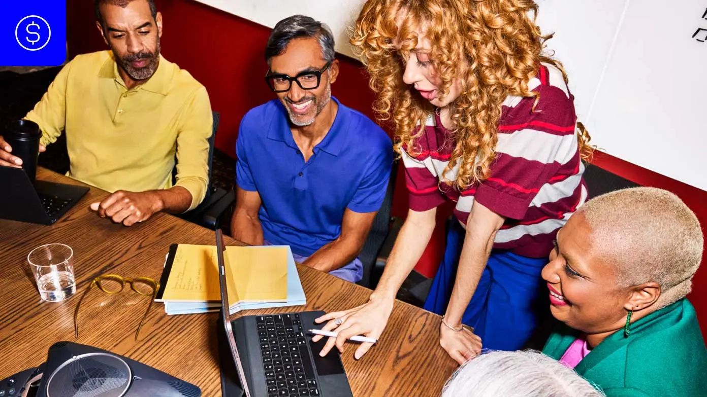 a group of people gathered around a wooden table in what appears to be a casual meeting or discussion​​ 
