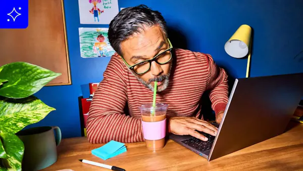 a man sitting at a wooden desk, focused on his laptop