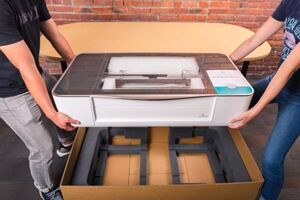 Two people lowering a Glowforge into its shipping box