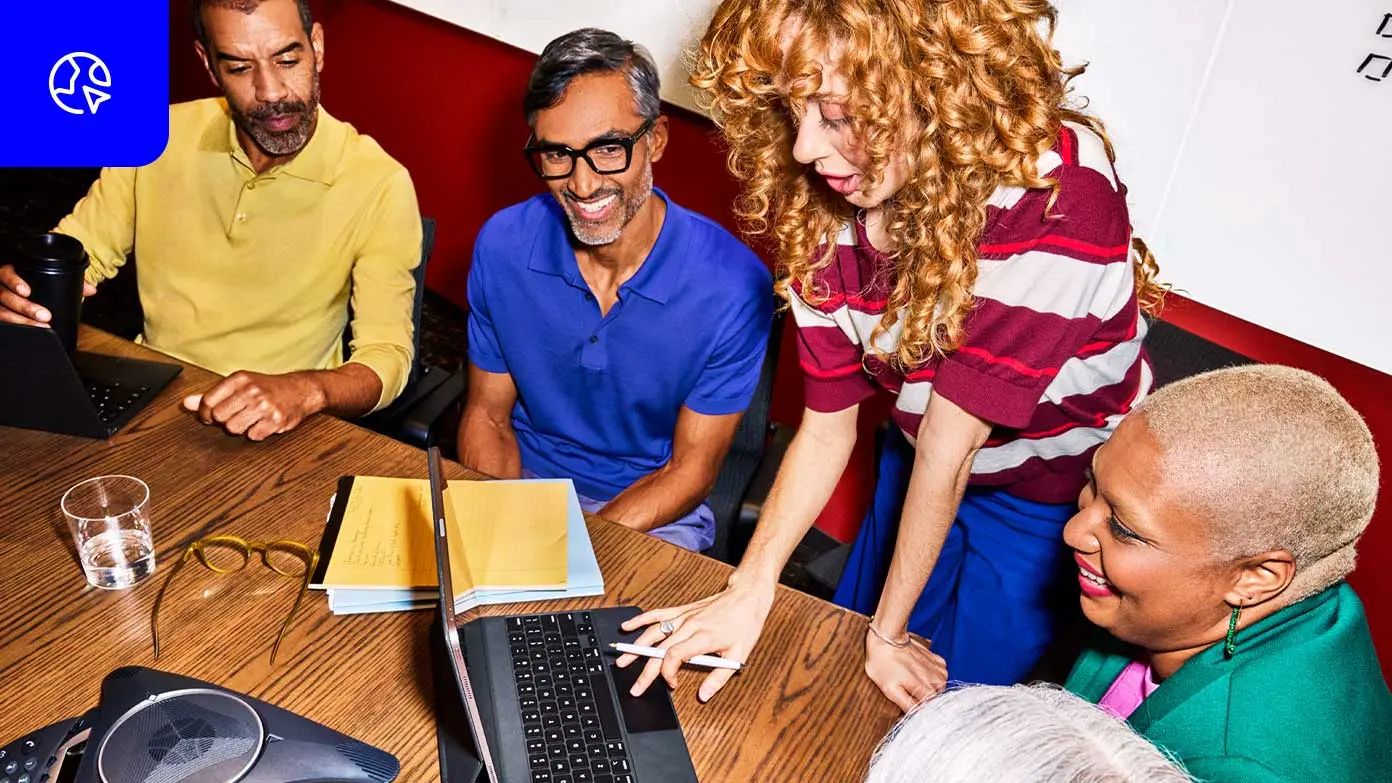 sekelompok orang berkumpul di sekitar meja untuk melakukan pertemuan atau sesi kerja kolaboratif