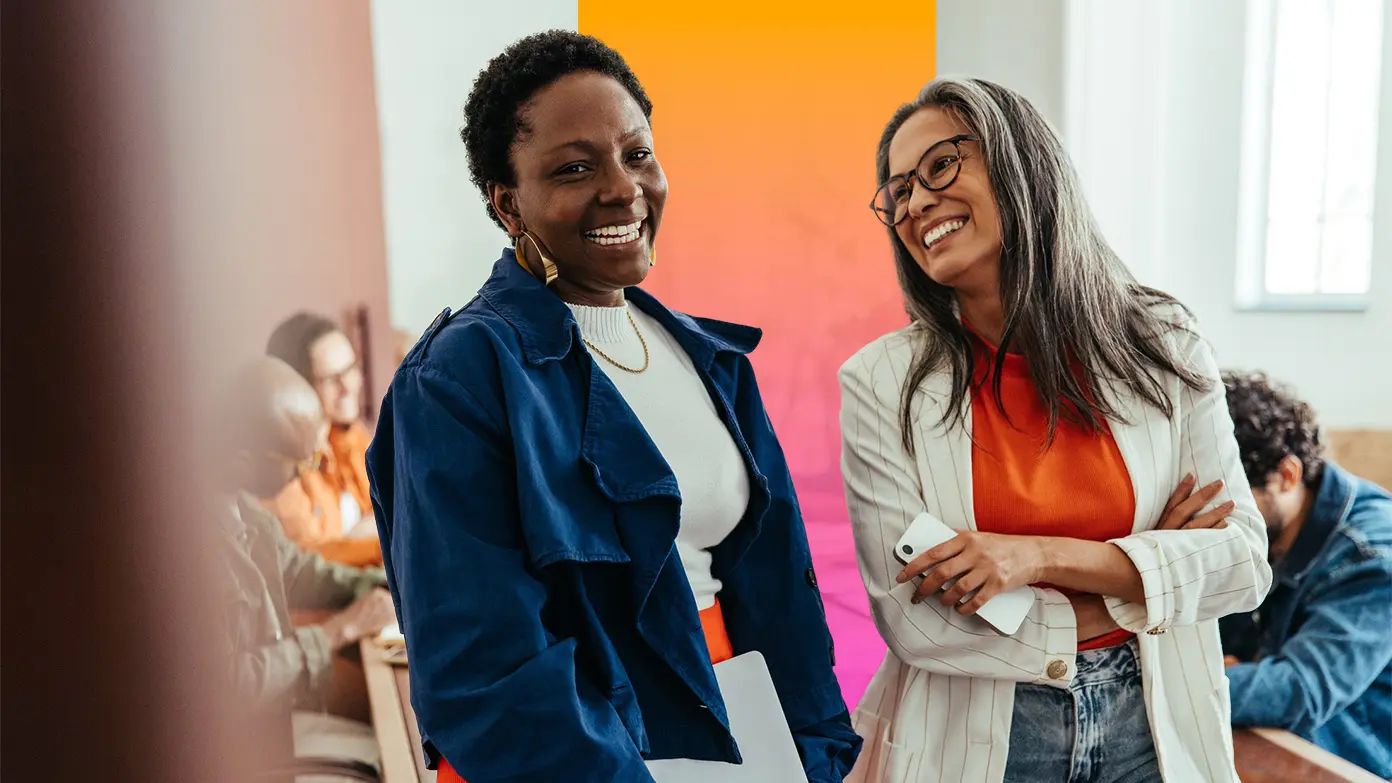 two businesswoman standing in conference room and smiling