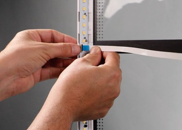 The cable being inserted into the socket along the LED strip on the left side of the lid