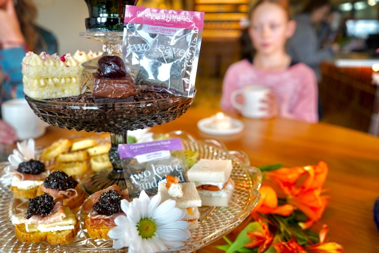 Assorted afternoon tea sandwiches and desserts on cake tray with tea
