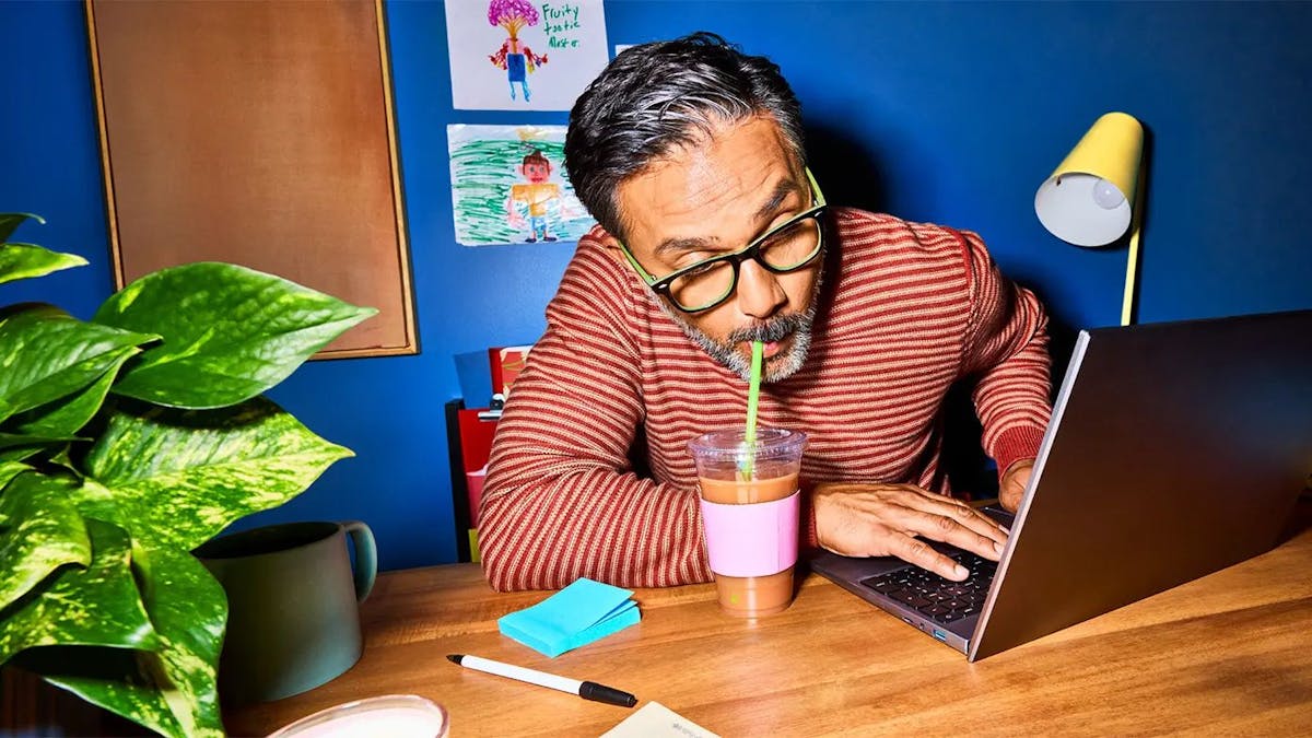 un uomo seduto a una scrivania di legno, che lavora su un computer portatile