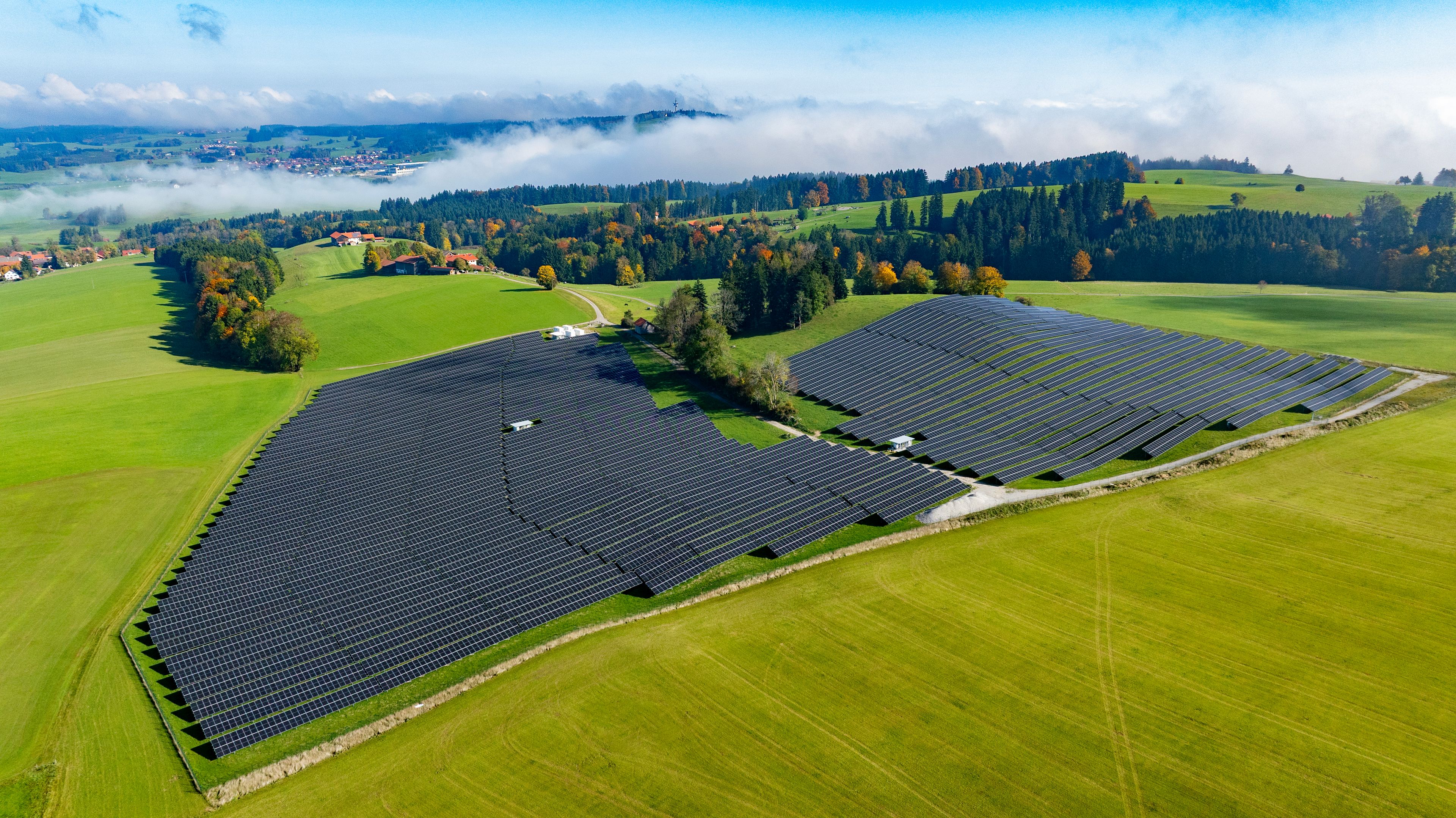 Image Attributed to: Nextpower. Image shows an aerial view of a solar project on verdant forest land. 

