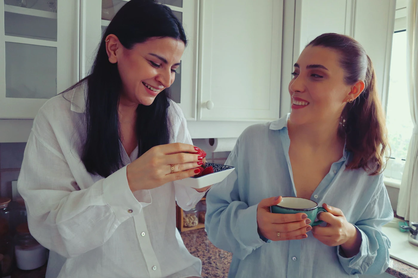 Best friends laughing over coffee wearing Zayla rings