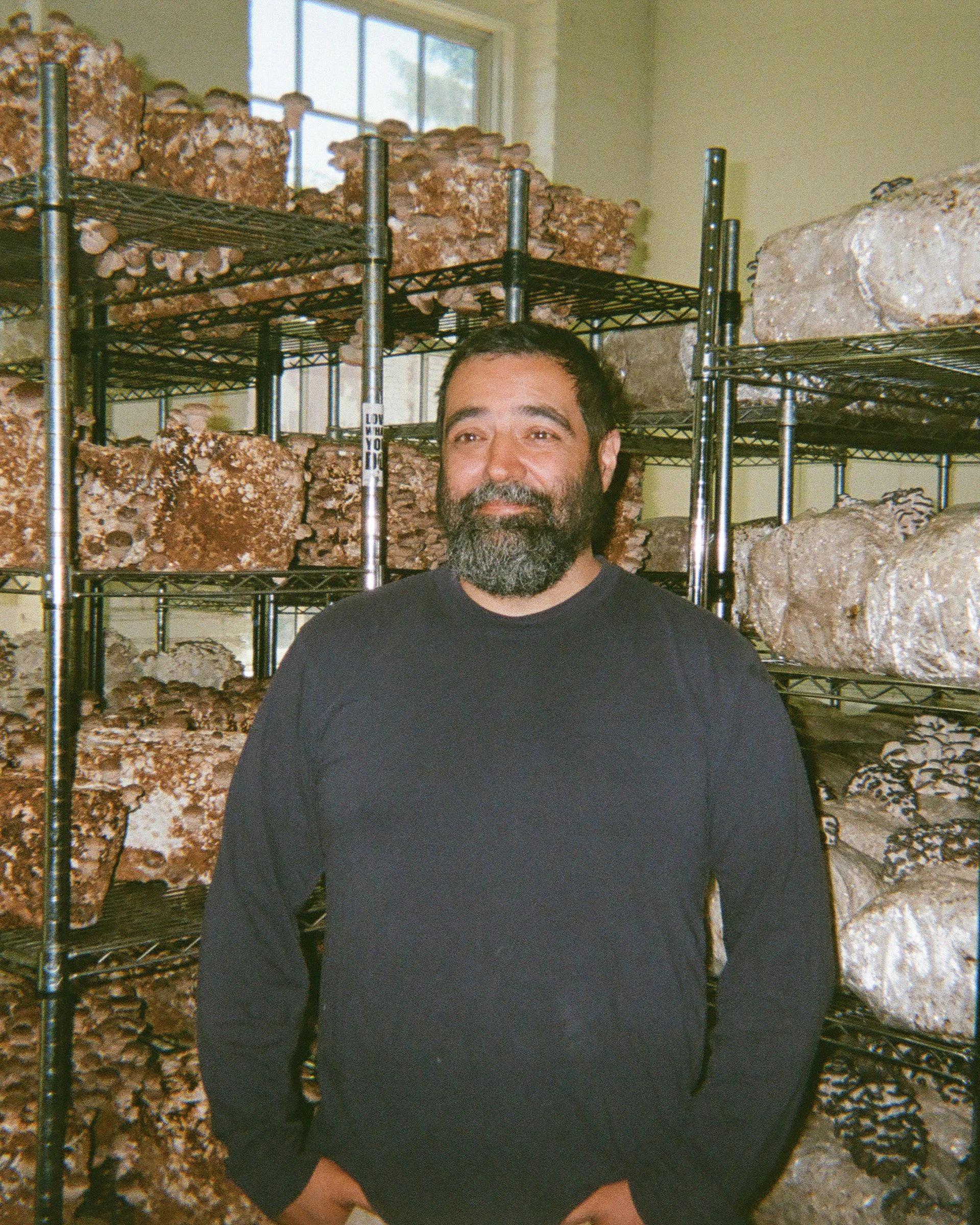 Robbie standing in front of racks of growing mushrooms