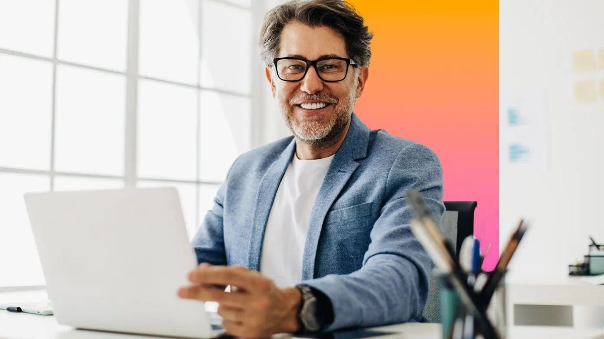 Mature man smiling and working at laptop