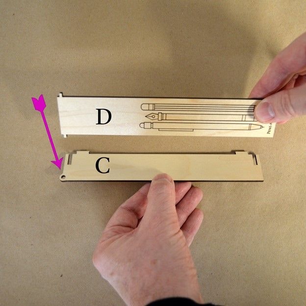 Two hands connecting wooden laser cut parts labeled D & C