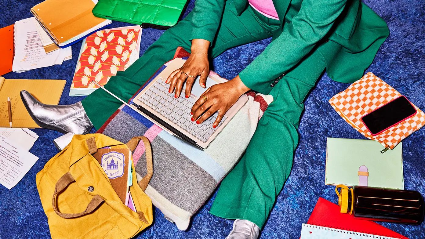 person wearing green suit sitting on the floor and working on a laptop