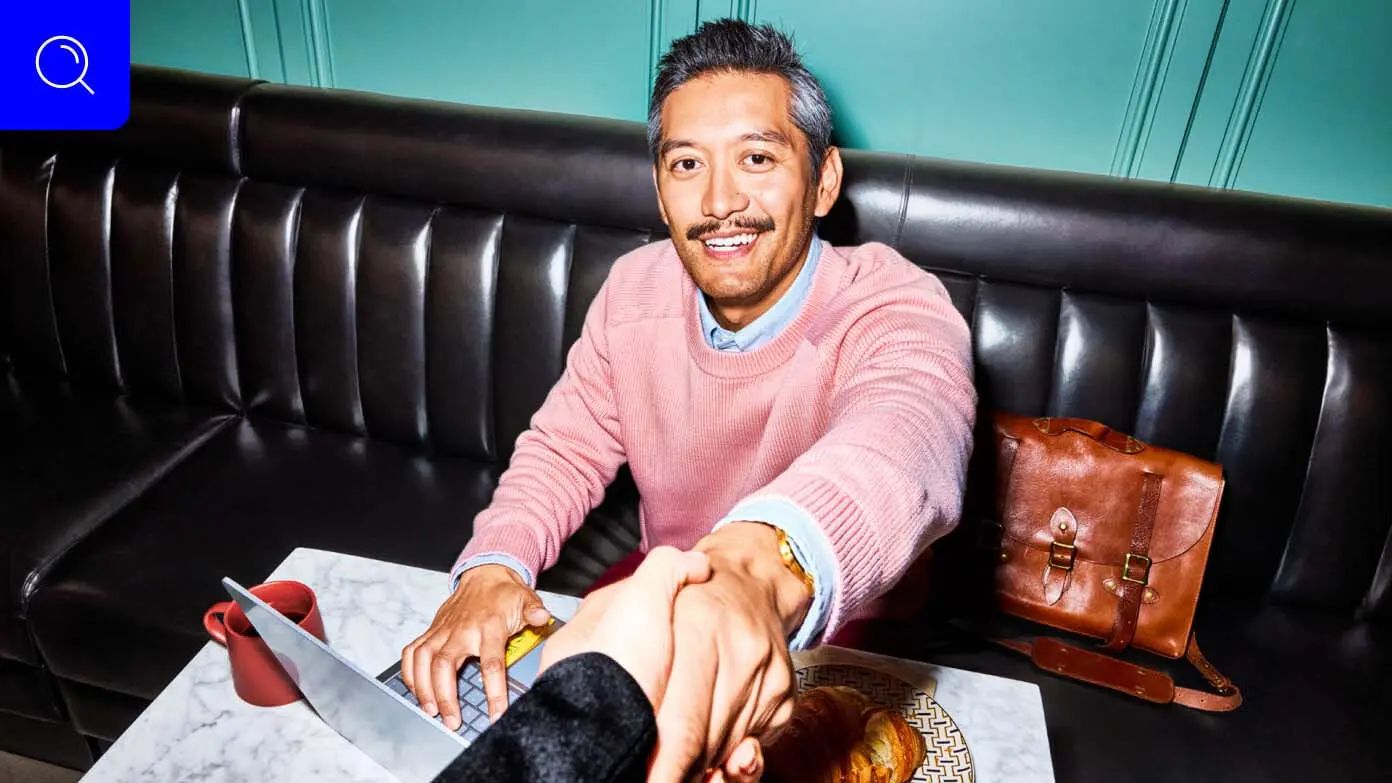  a man sitting on a black leather bench in what appears to be a cafe or a restaurant​​ 