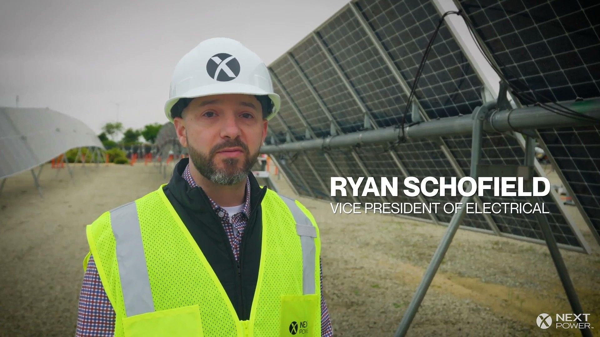 Image Attributed to: Nextpower. Nextpower employee standing in front of an electrical balance of system component on a utility-scale solar tracker.