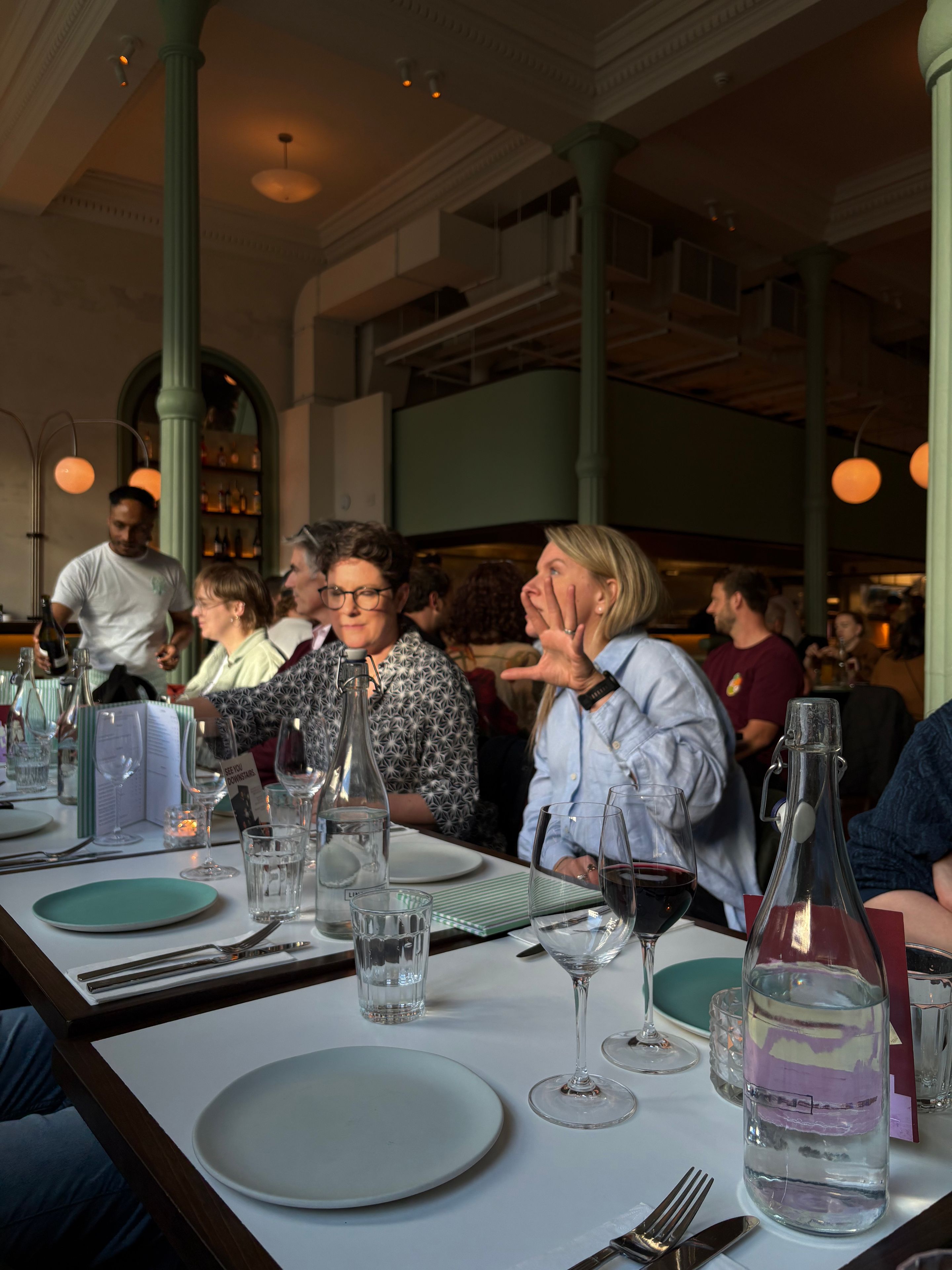 Some of the team seated at a long table at a restaurant, chatting