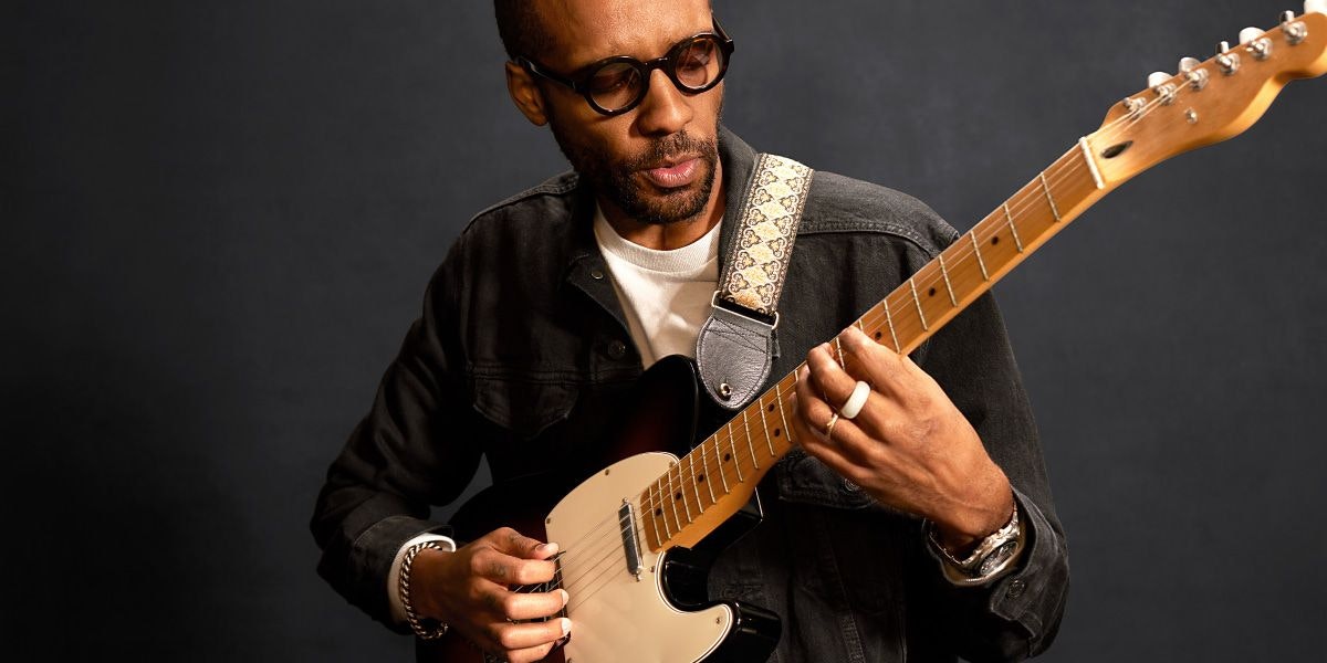 Person playing guitar against a dark background
