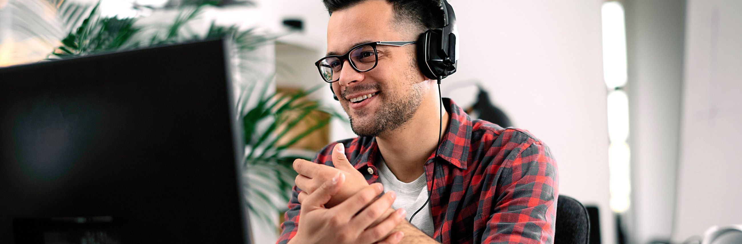 Person wearing headphones and working at a computer in an office.