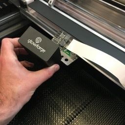 A hand removing the print head from the carriage plate it rests on inside the Glowforge.
