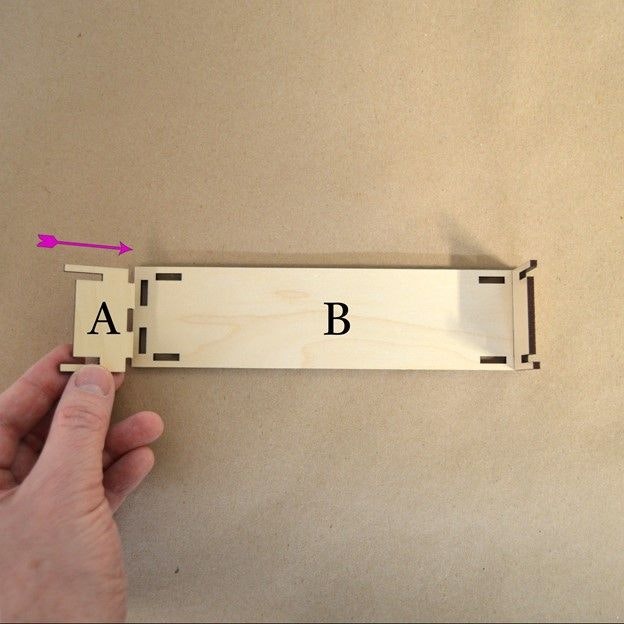 Two hands connecting wooden laser cut parts labeled A & B