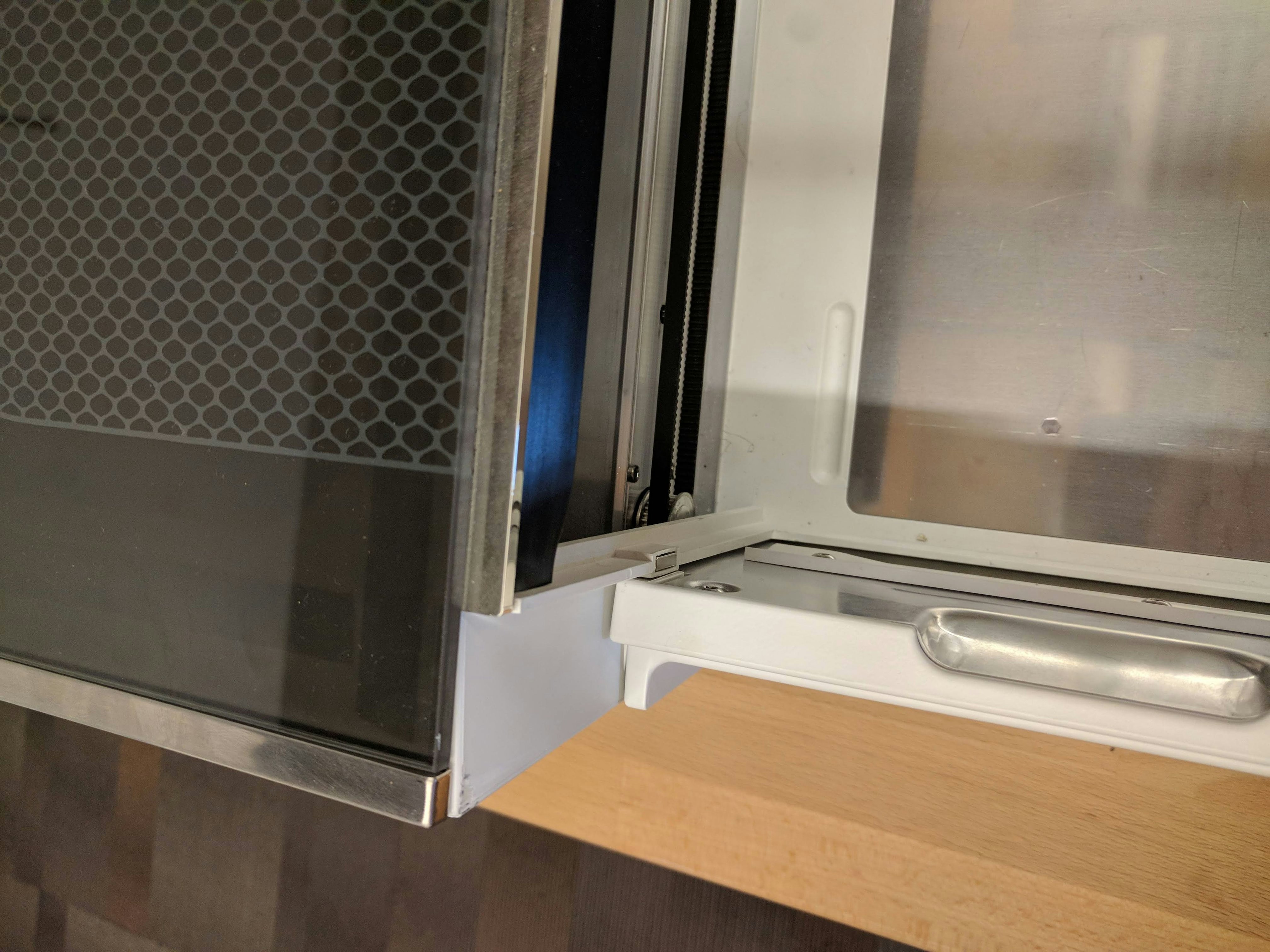 The left side of the closed front door of the Glowforge with the lid open. The door closes completely and there is no damage.