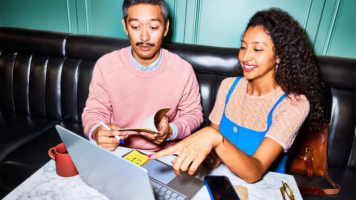 man and woman discussing project while looking at laptop