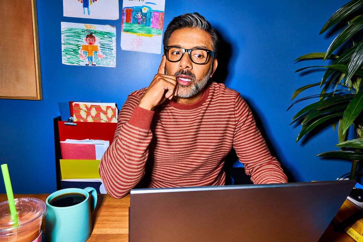 A HR manager in his home office looks thoughtfully at his laptop screen while learning about the complexities of how to hire globally.