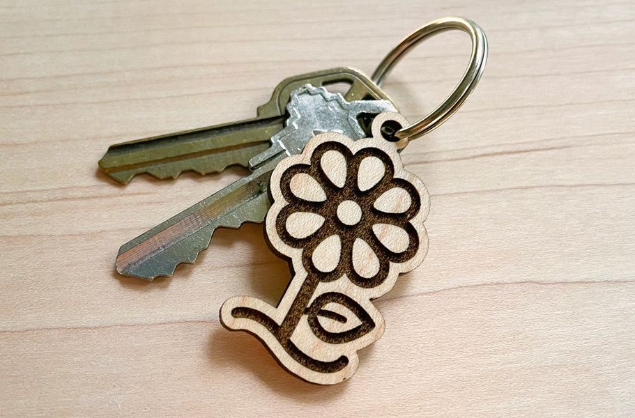 A completed, laser cut and engraved wooden keychain on a key ring with keys.
