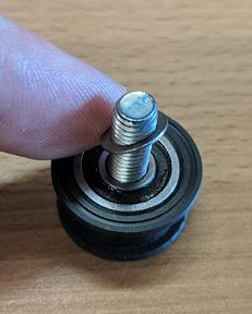 A new pulley with a screw inserted and washer placed on the screw