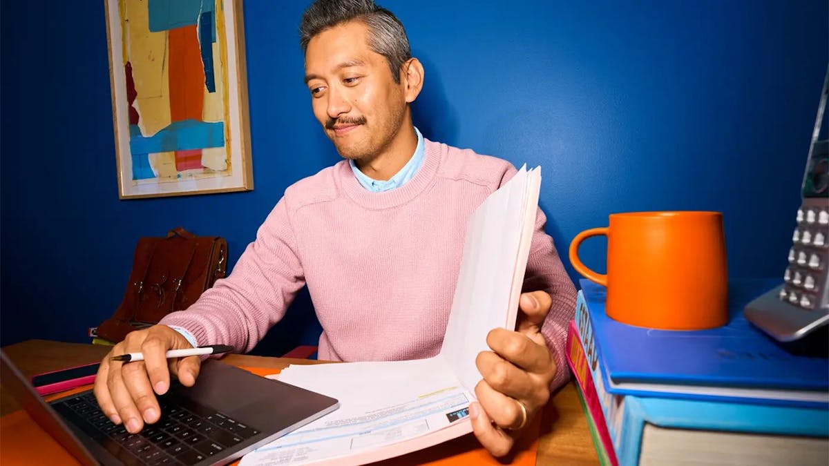 man working on laptop and looking at report