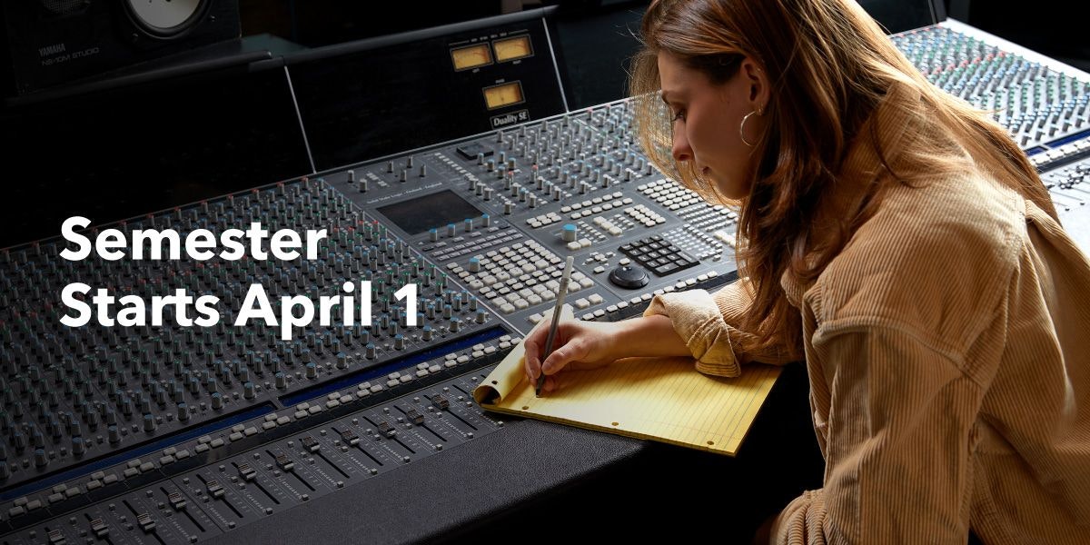 Person writing on a notepad on a mixing console.