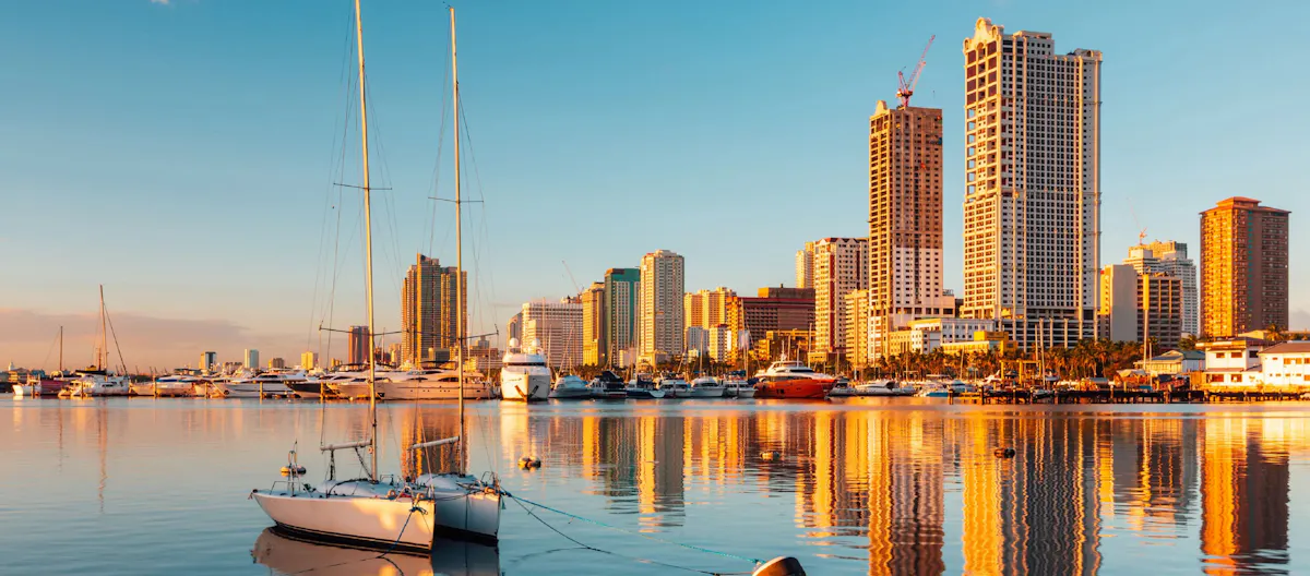 The Manila Bay skyline with yachts in the harbor at sunset, for a guide on recruiting and hiring in the Philippines.