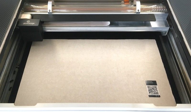 A sheet of Proofgrade material in the bed of a Glowforge, with the lid open.