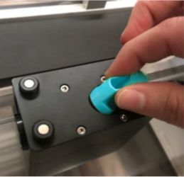 A hand grasping the blue handle of the print head mirror