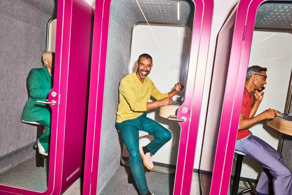 three individuals seated in separate pink booths working on creative workplace
