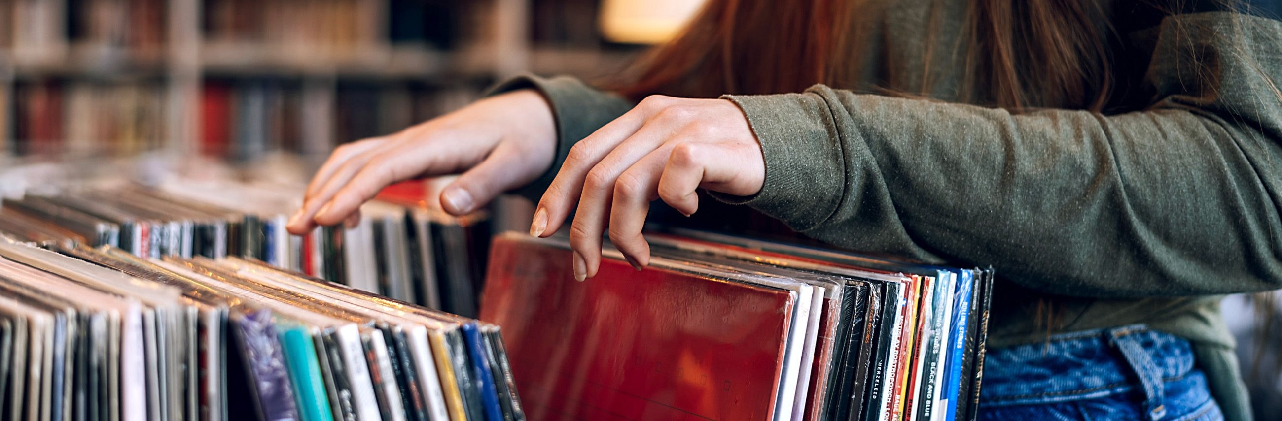 Woman's hands flipping through vinyl records in record shop.