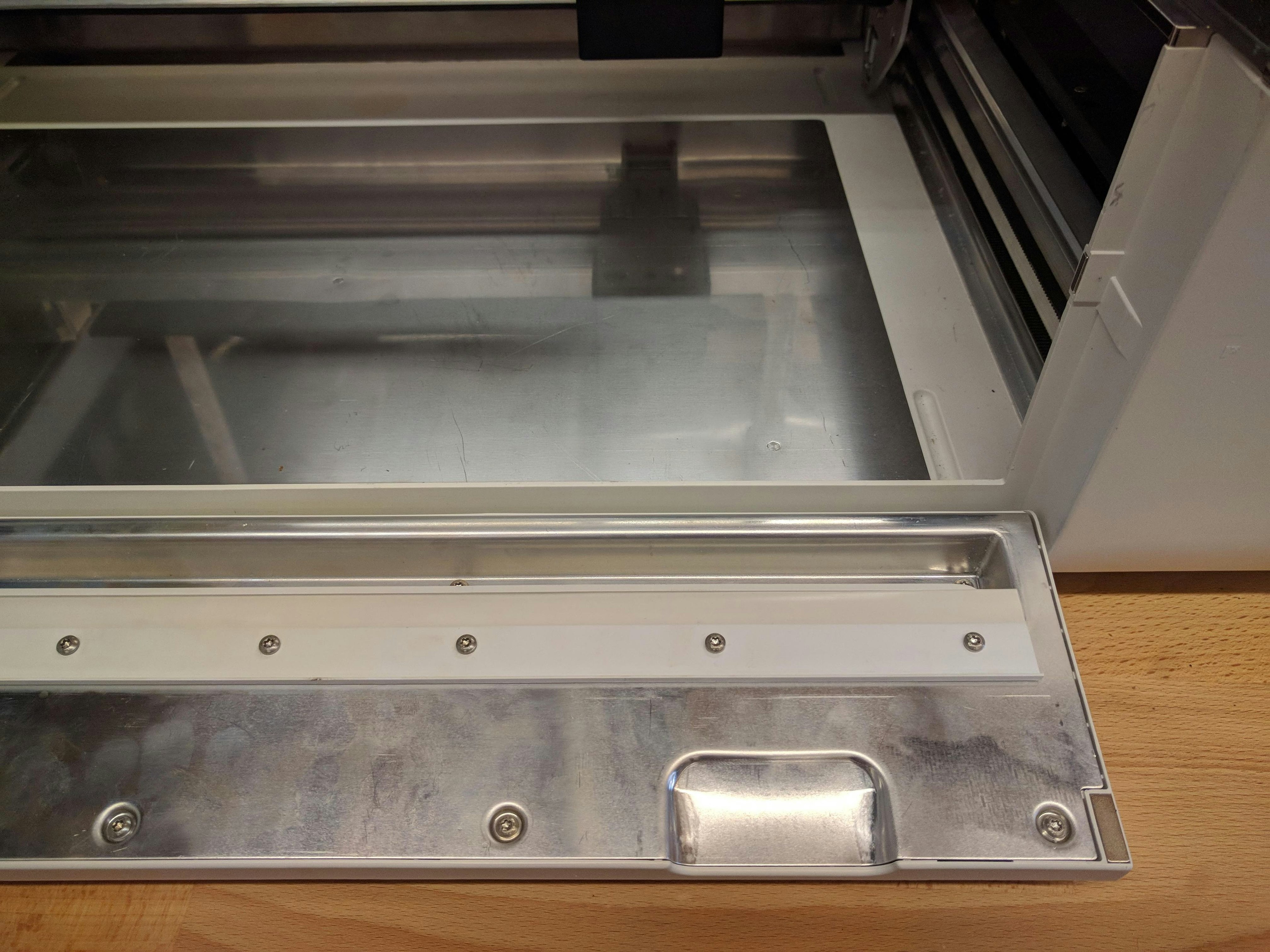 The right side of the open front door of the Glowforge. There is no debris present and the door is undamaged.